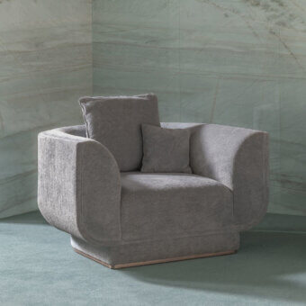 Distinguished Visionnaire Foster lounge chair with textured fabric upholstery, canneté stitching and a polished stainless steel plinth base