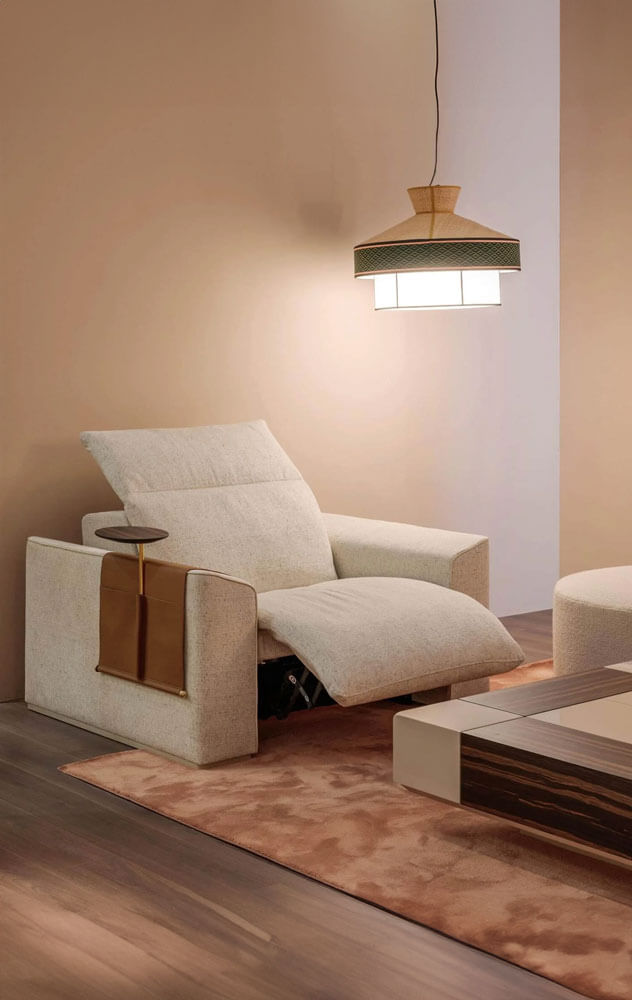 Home cinema recliner, light beige textured fabric, angled backrest with integrated side table, terracotta rug, woven pendant light.