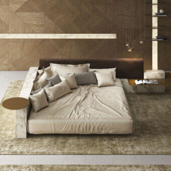 Elegant Laurameroni Symphony Bed with ceramic‑clad structure, black aniline‑dyed wood base, padded velvet headboard, white marble‑like surround with grey veining, beige and off‑white bedding, and natural brown wood side table