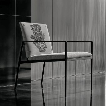 Sophisticated JR Home by John Richmond armchair upholstered in textured textile with black glossy frame and laser etched motif