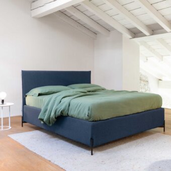 Luxury Noctis Cosmo bed in deep navy blue textured textile upholstery with low-profile silhouette and dark metal legs